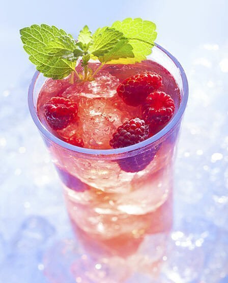 cold refreshment with raspberries, mint and soda on ice cubes