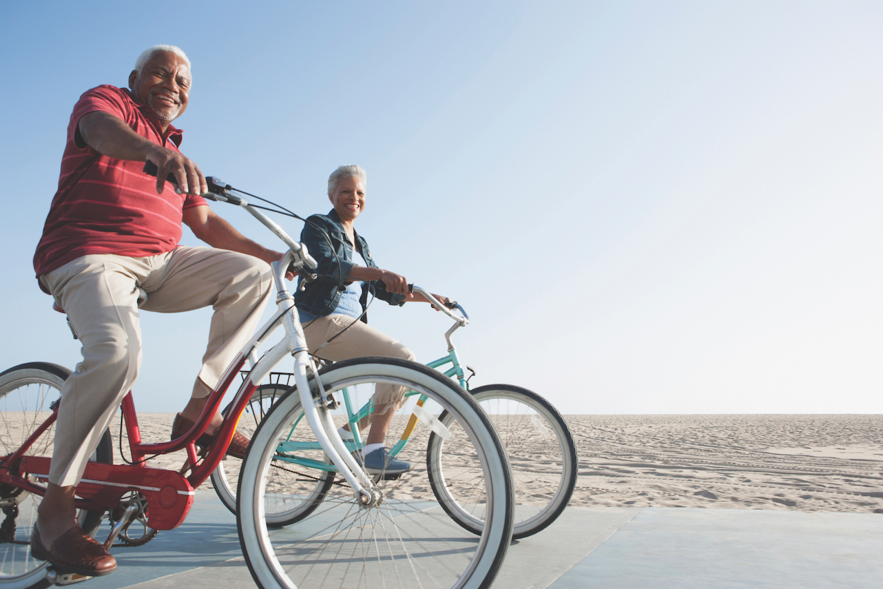 Senior African American couple riding bicycles by beach