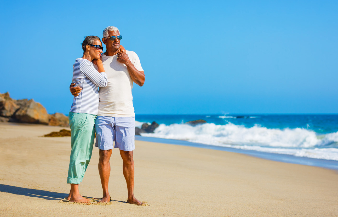 Senior African American couple embracing on beach